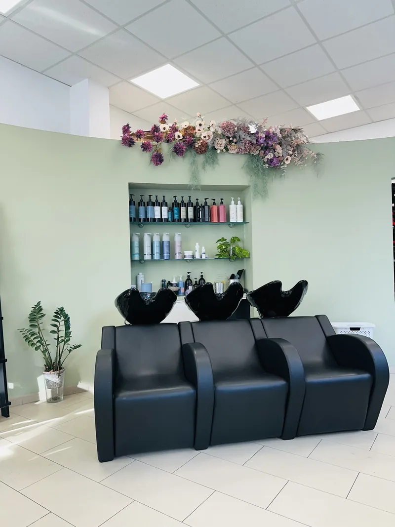 L'espace bacs du salon — fauteuils noirs, mur vert sauge et décor floral